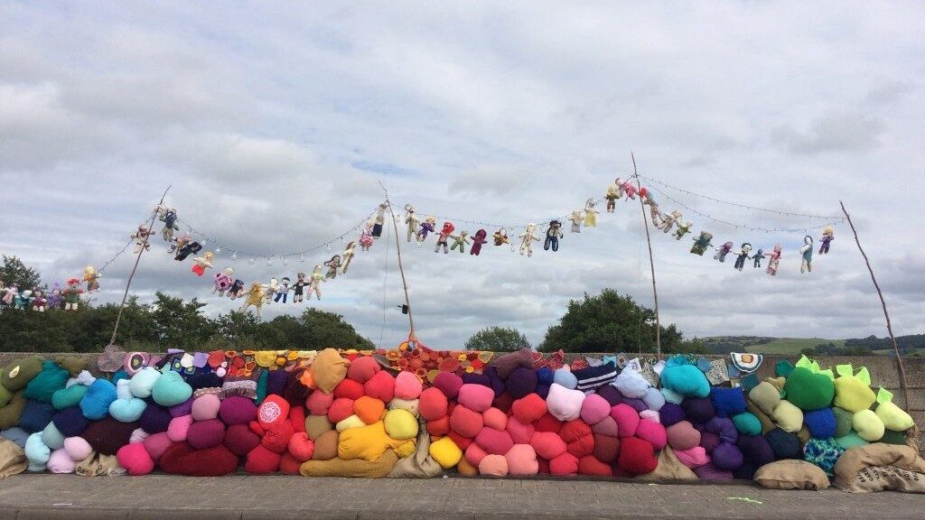 Image of dolls and colourful cushions outsides ate a border