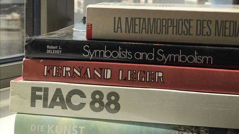 Pile of five books near a window with skyline view.