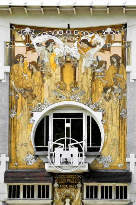The colourful facade of a townhouse, painted with many women holding symbols of industry and art.