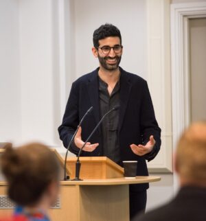 Man standing at a lectern giving a lecture.