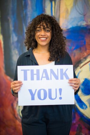 A student smiling and holding a 'Thank You!' sign