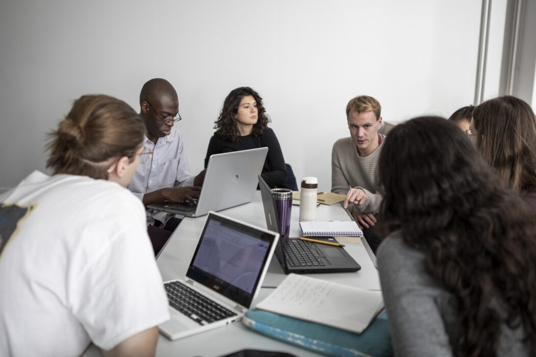 Students at a desk with laptops.