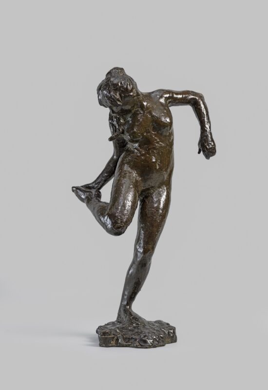 A bronze sculpture of a dancer looking at the sole of her right foot