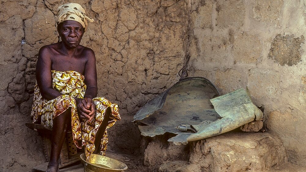 Photograph of a woman sitting with a gold bowl in front of her