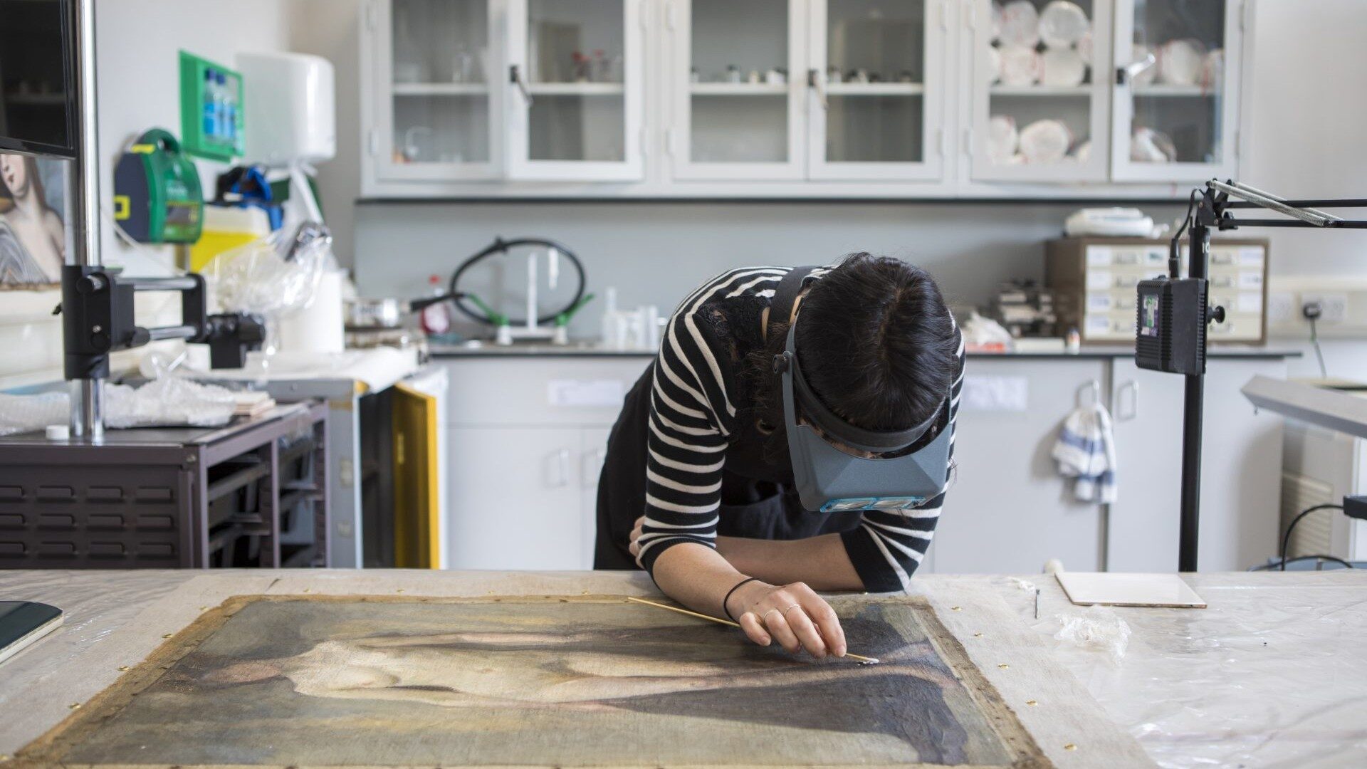 student in the conservation studio swabbing a painting
