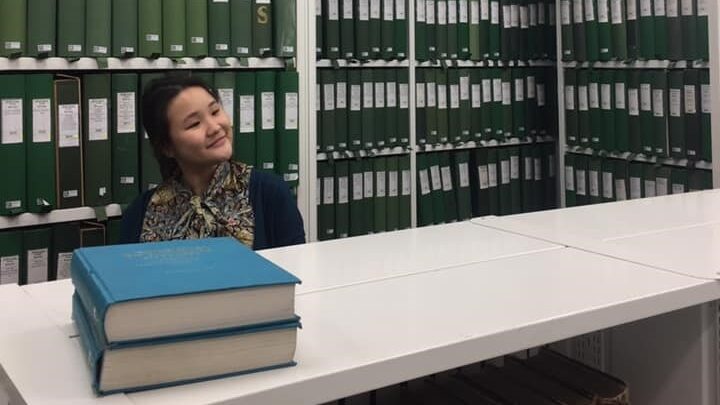 Young woman in a library surrounded by files