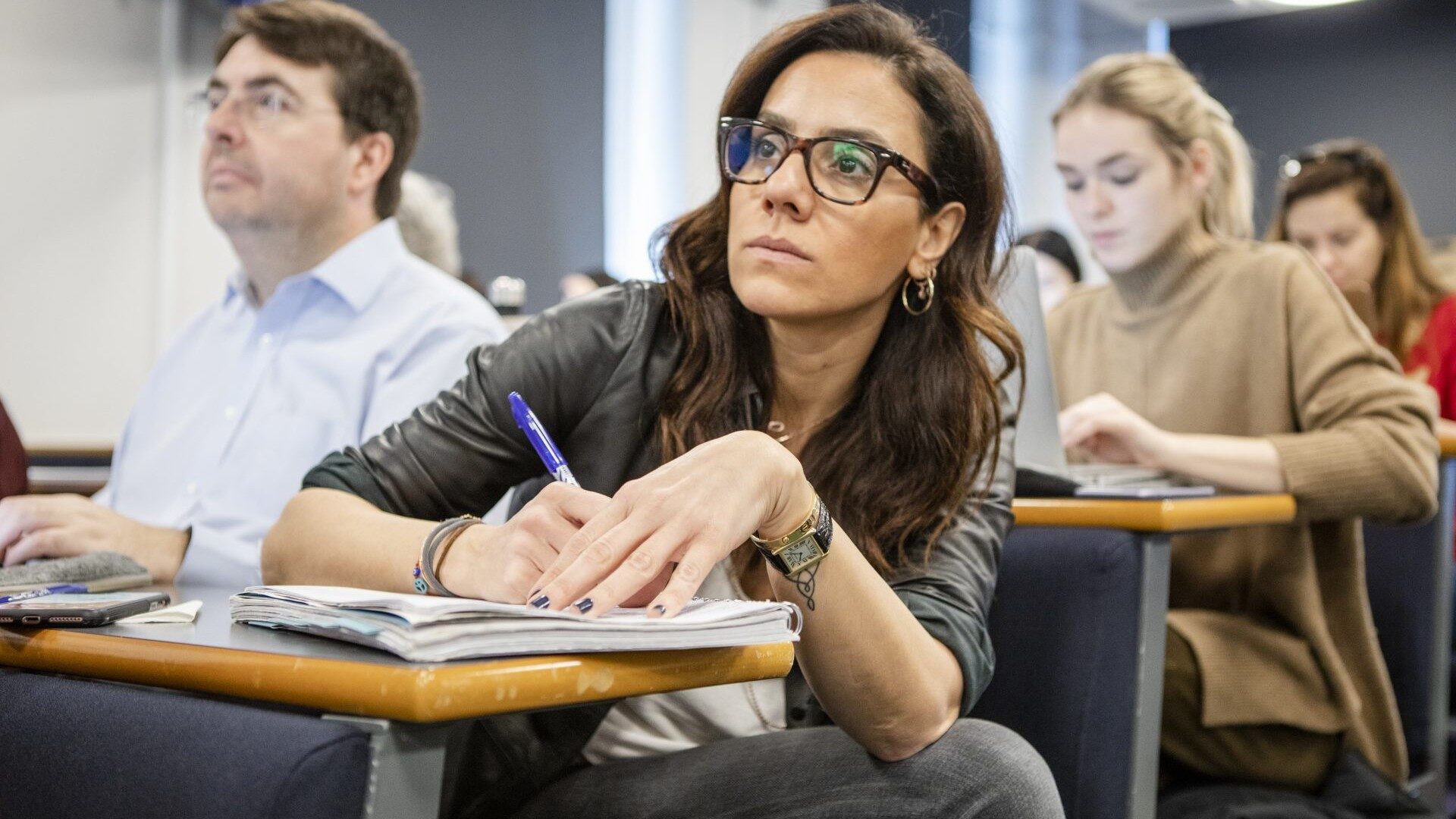 close up of a student taking notes during a lecture