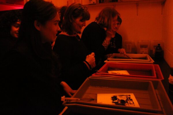 a group of students in a dark room developing analogue film