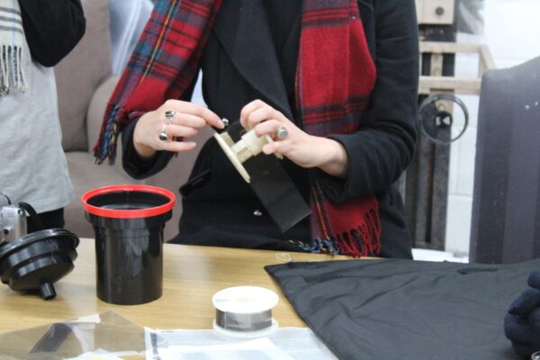 a person demonstrating how to thread a developing reel with film