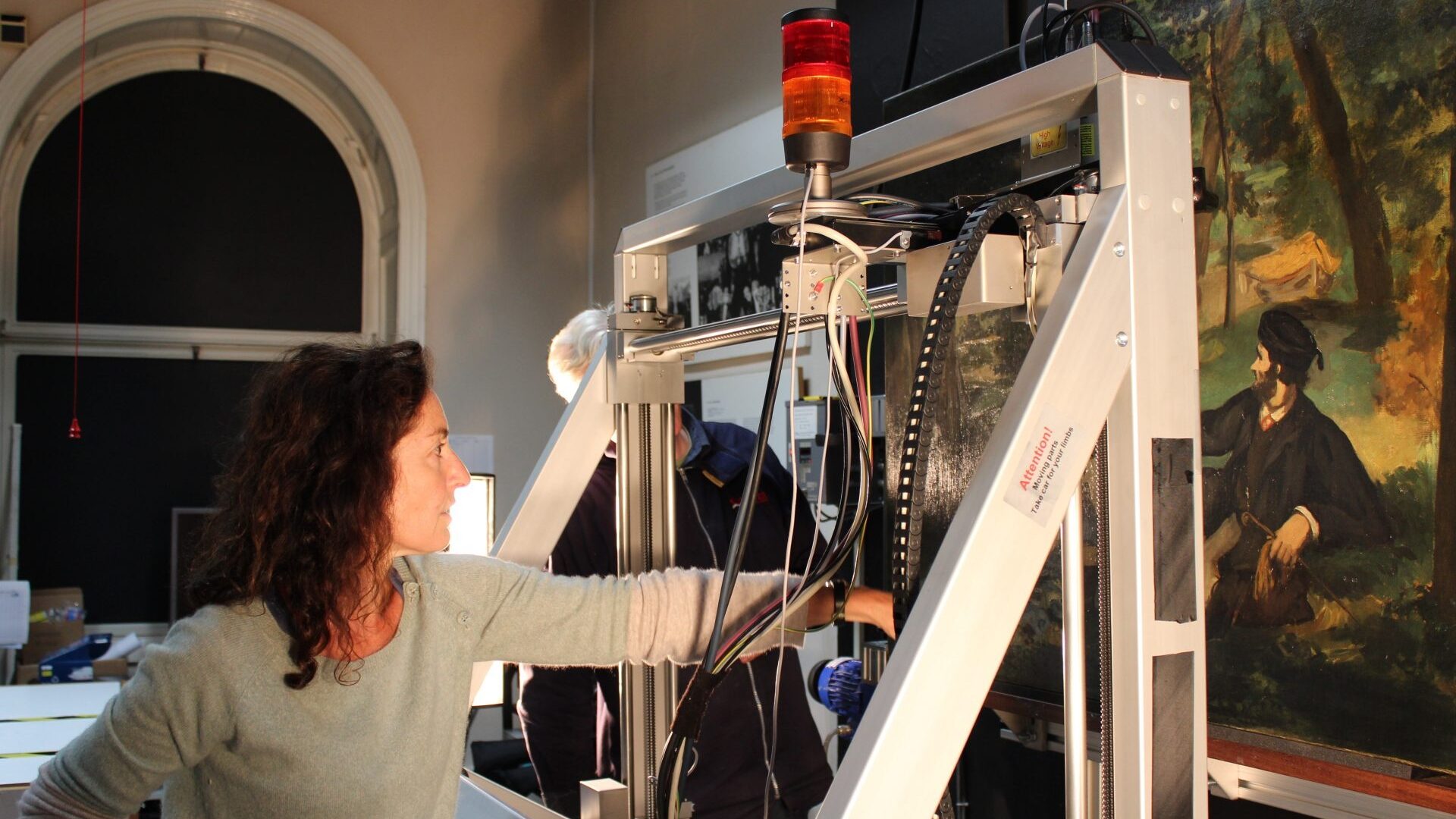 Woman using technical equipment to examine a painting
