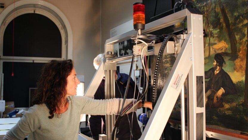 Woman using technical equipment to examine a painting