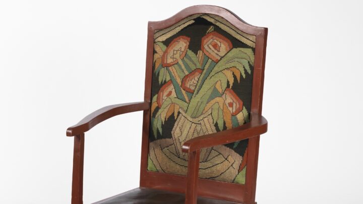 A chair with an embroidered floral seat back and a black seat cushion