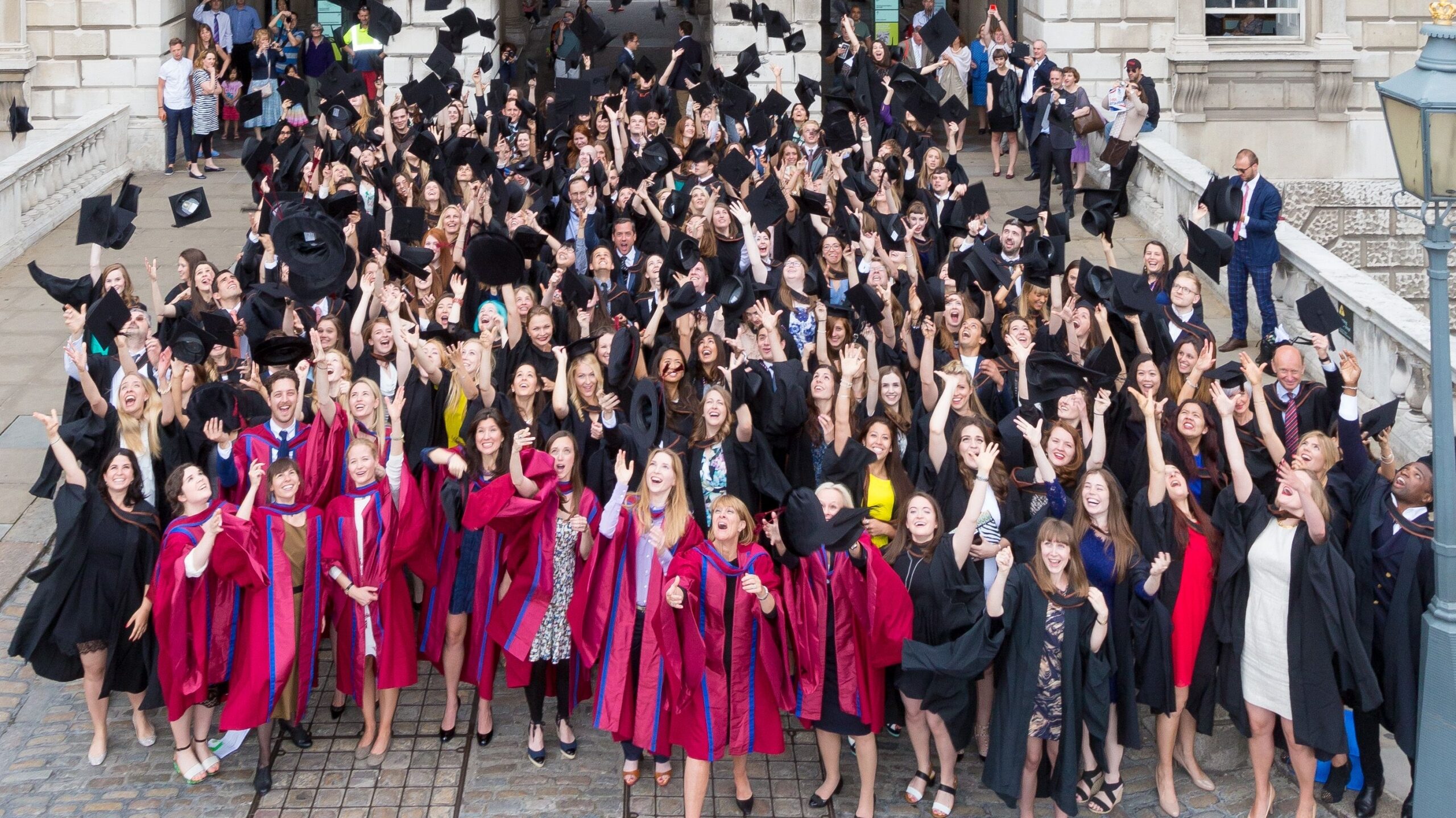 Graduates throwing mortar boards in the air at Graduation