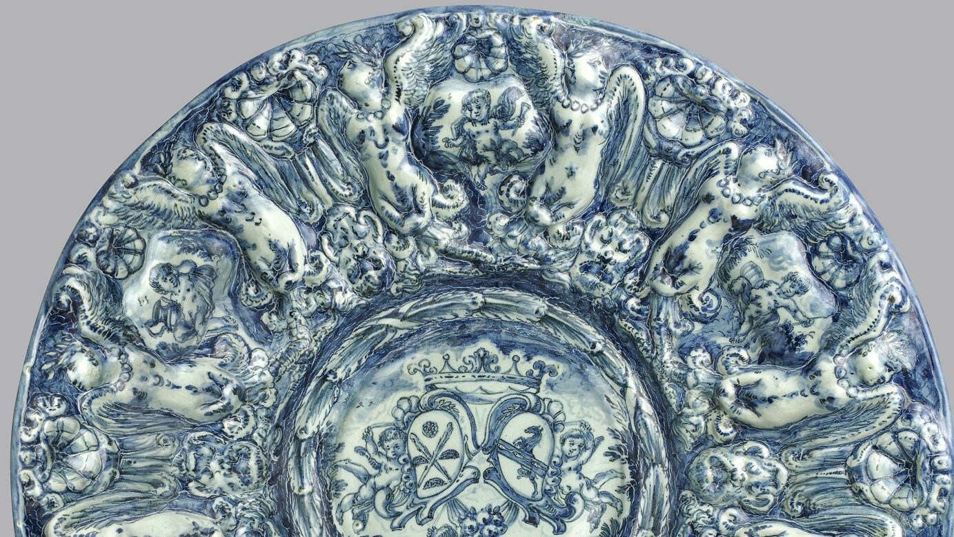 Large moulded dish with Harpy border decorated in blue with a putto supporting a double coat-of-arms in centre flanked by putti and surmounted by a coronet