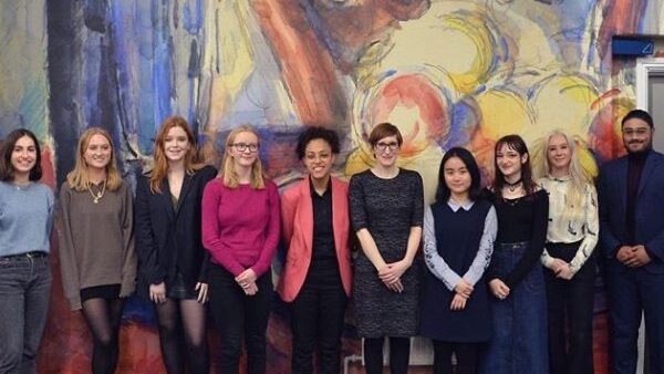 10 people pose for a photo, smiling, in front of a wall at The Courtauld.