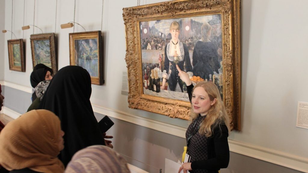 A woman pointing to a painting in a gallery