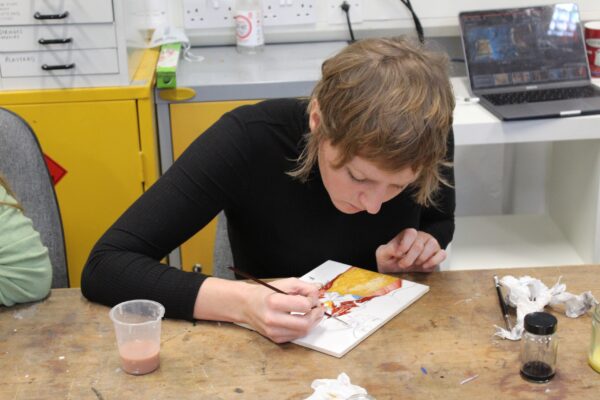 a student painting using pigments they've mixed into oil paint