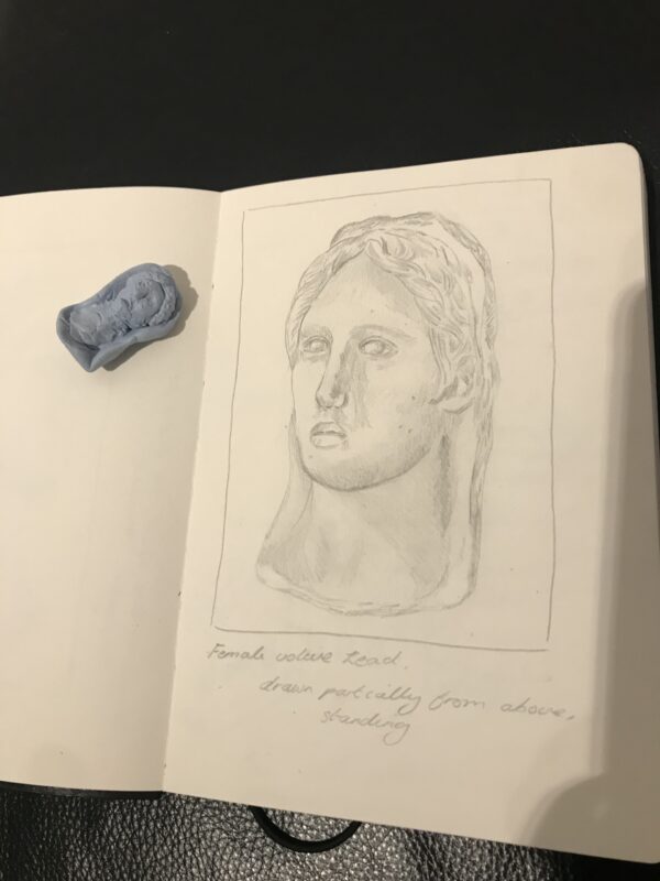 a sketch of a bust in pencil with a small blue tack maquette