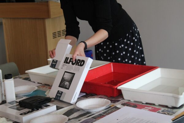 a teacher holding up a box of Ilford photographic paper