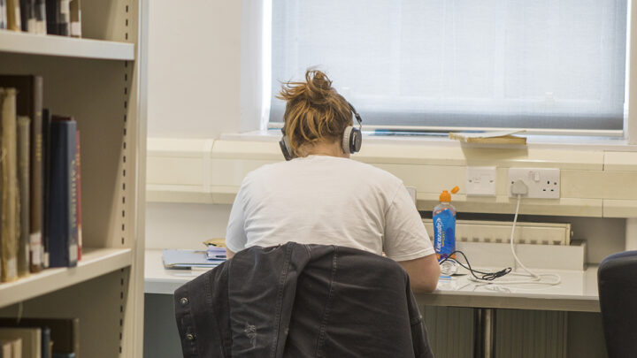 Student studying in the Library with headphones