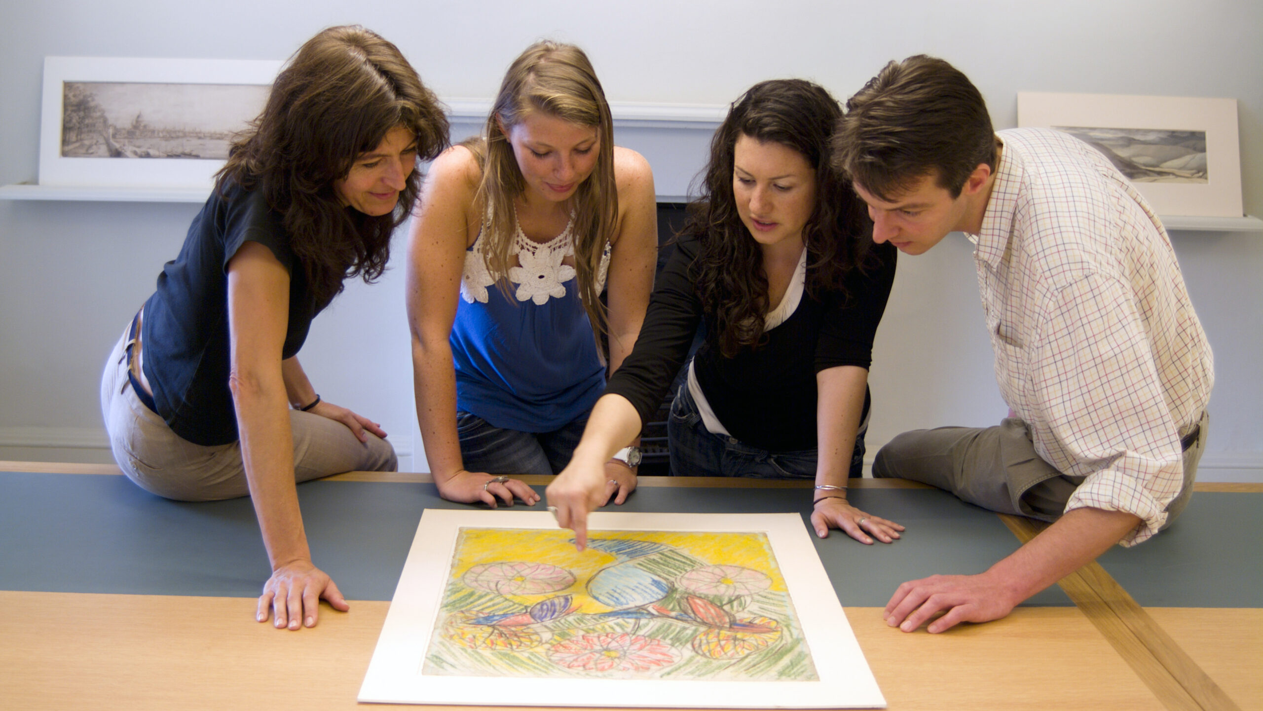 Students gathered around an artwork laid out on a table.