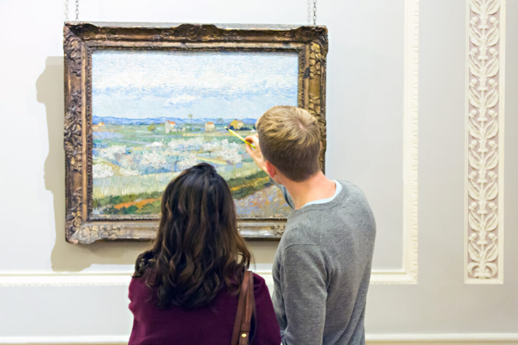Two people standing in a gallery looking at a painting