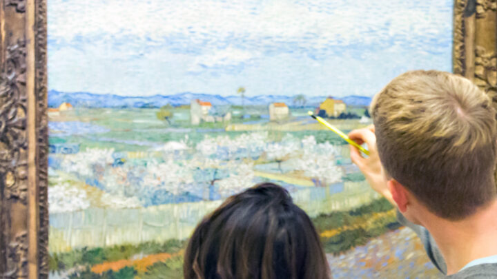 Two people standing in a gallery looking at a painting