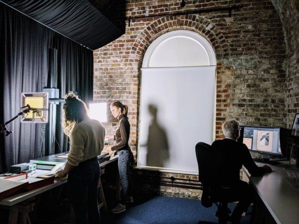 Photograph showing people digitising images in a dark interior