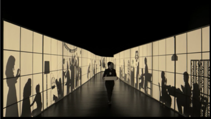 a figure walking down a dark corridor with projections on either side