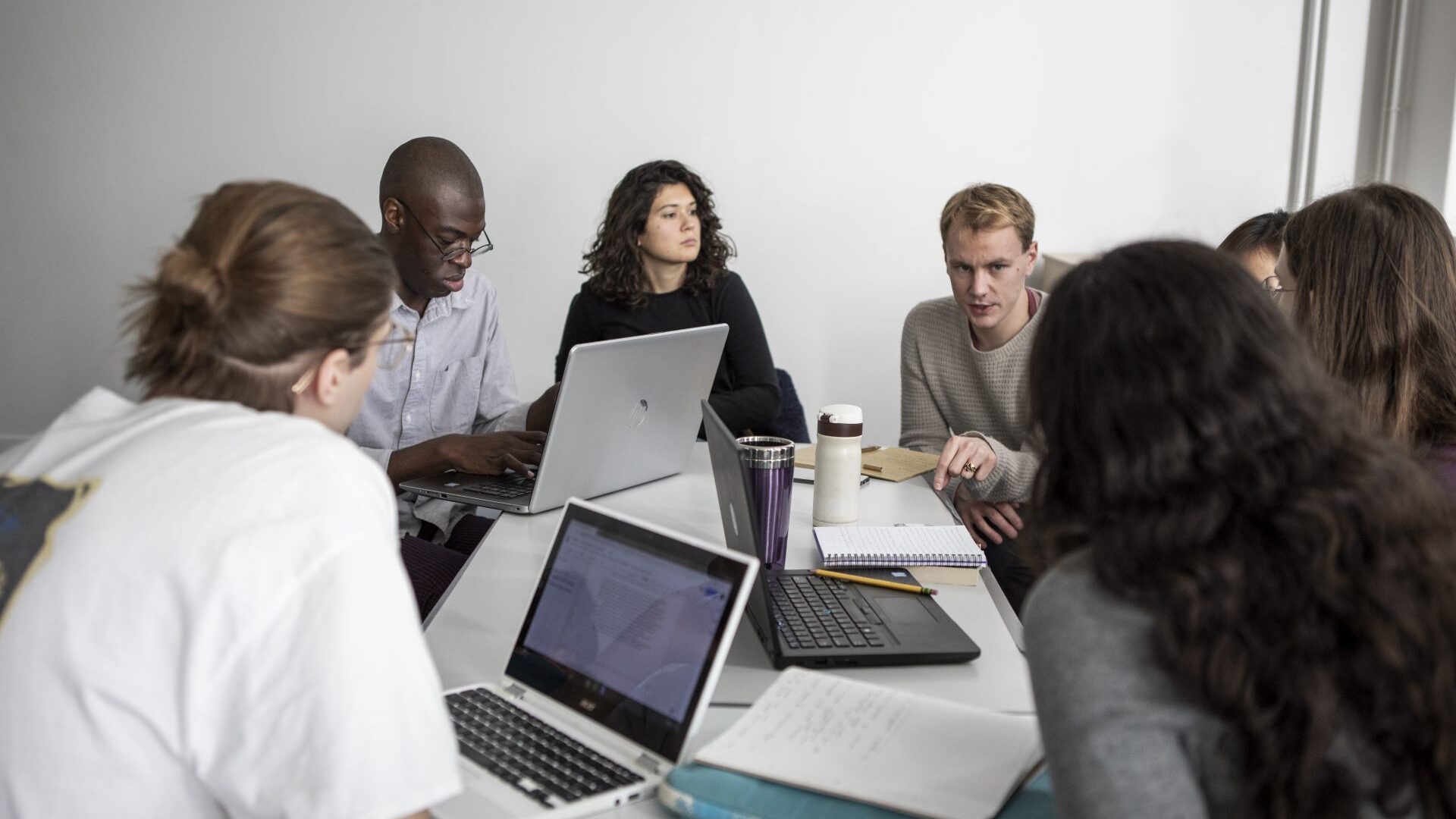 group of students sat around a table discussing and taking notes as part of a study group