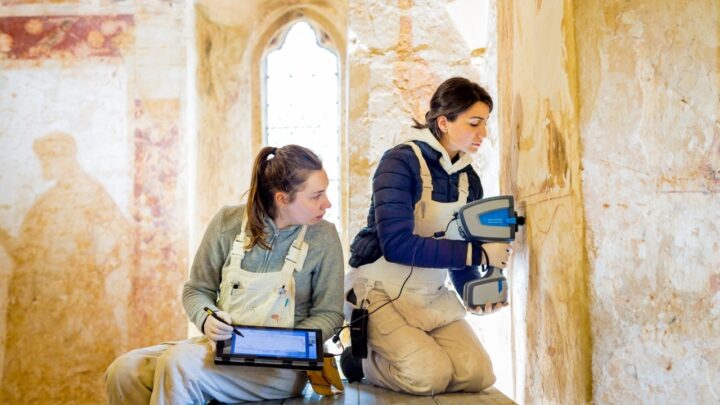 Two conservation students working on a wall