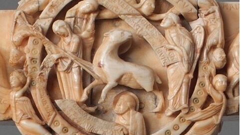 Close up photograph of the centre of an intricately carved cross made of ivory.