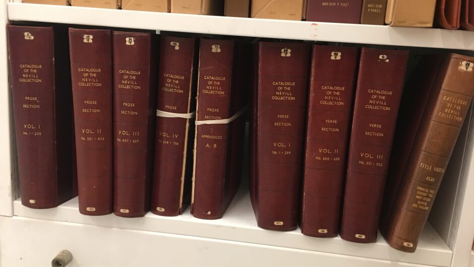A photograph of a shelf of identical books with burgundy covers and gold writing