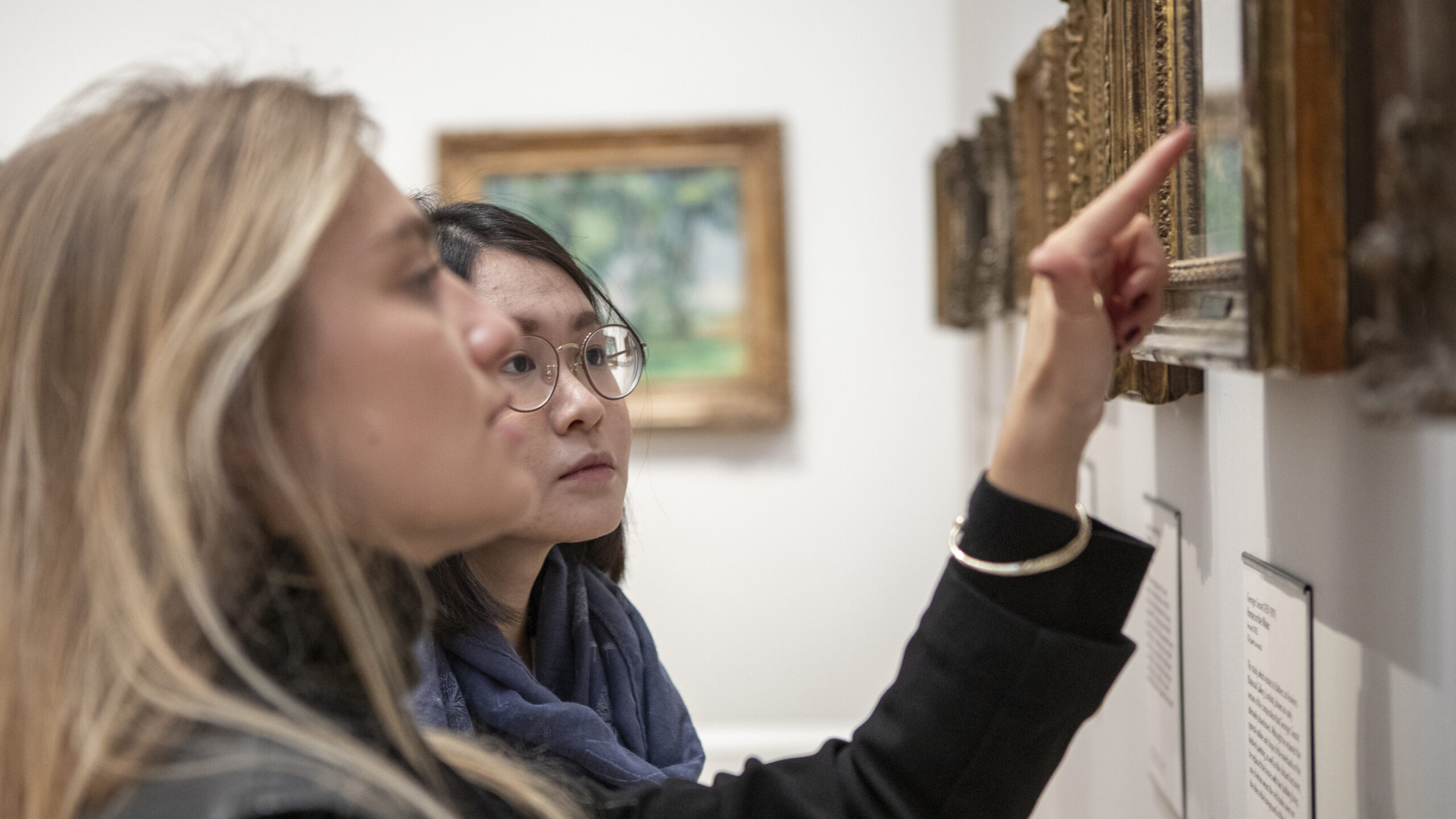 two young women standing in front of a painting in the Courtauld's gallery