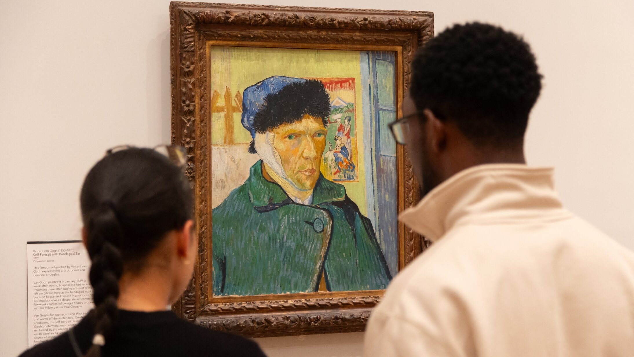 Two visitors look at Van Gogh's self portrait with bandaged ear