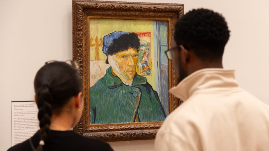 Two visitors look at Van Gogh's self portrait with bandaged ear