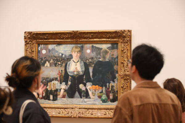 Two visitors look at Manet's A Bar at the Folies Bergere