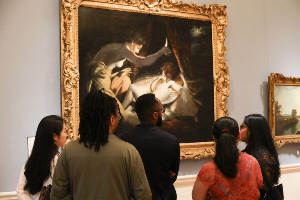 A group of visitors gather around a painting at The Courtauld Gallery