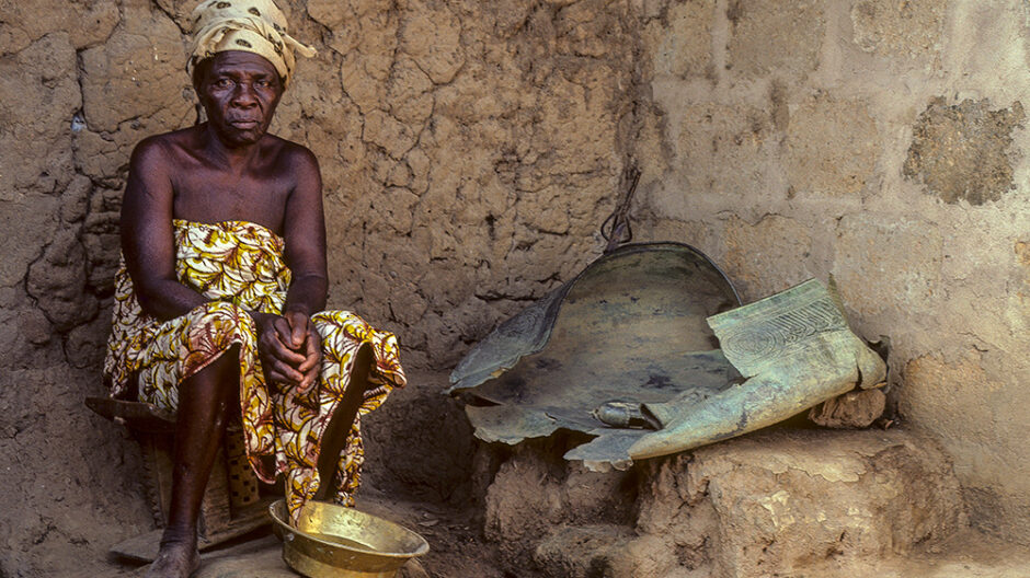 Photograph of a woman sitting with a gold bowl in front of her