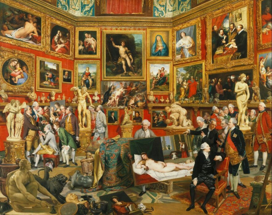 People look at and discuss art in a grand room filled with paintings and sculpture