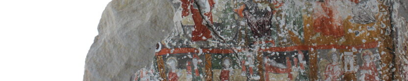 Image of an incomplete wall depicting a cross. The wall is missing a section at the top and sections of rock are visible in the background through this gap.