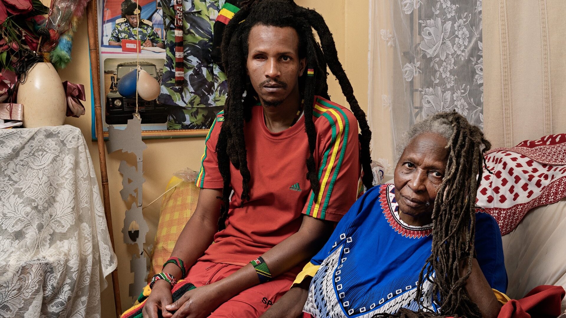 Photograph of a young man and older woman sat on a sofa