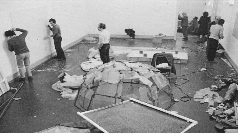 Photograph in black and white showing the installation of an exhibition in a white room