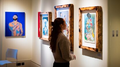 A woman stands in a gallery looking at artworks on the wall