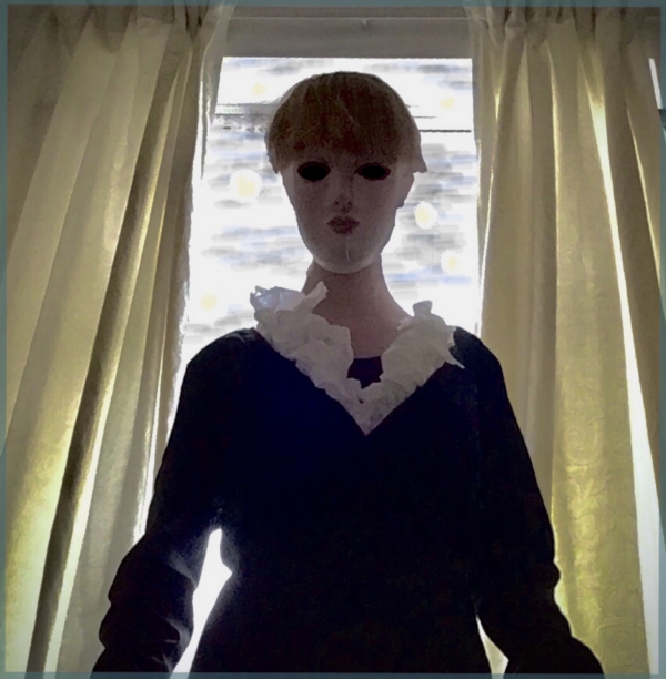 A photograph of a lady, in front of some curtains. Lady is wearing a paper mache mash.