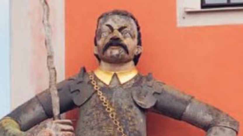 Cover of a book titled 'Giants in the Medieval City' by Assaf Pinkus showing a large medieval sculpture of a man with a sword standing outside some buildings