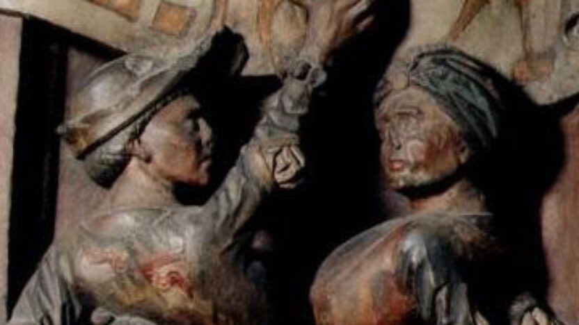 Photograph of two medieval figures dancing on a carved relief.