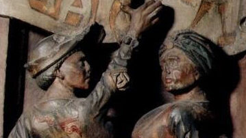 Photograph of two medieval figures dancing on a carved relief.