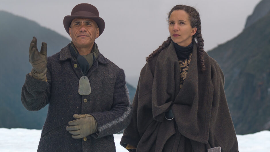 Two people in old fashioned clothes outdoors.