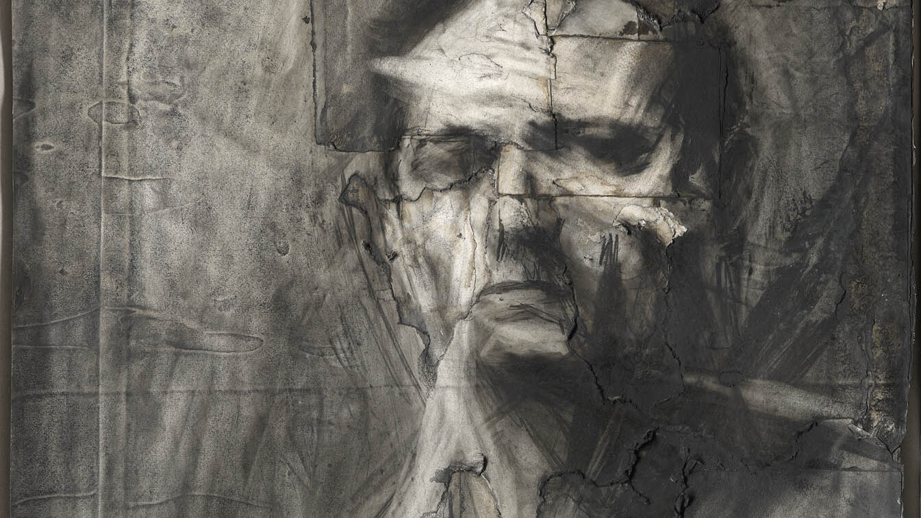 Charcoal drawing of a man, Frank Auerbach, sitting slightly side-on to the viewer and staring at us with a stern expression. The background is roughly completed, and the face somewhat fragmented by the background.